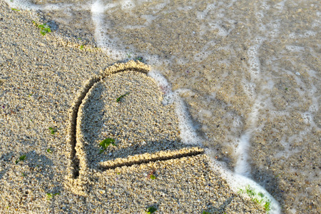 Sea beach sand waves and drawings of sun, love and heartの写真素材