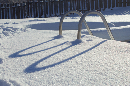 Ice swimming pool in the winter, Steps, hand-rails and garden chair in the frozen blue pool ice-holeの写真素材