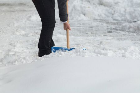 Business man with shovel cleaning snow filled street in front of the office at workの写真素材