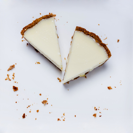 two slices of cheesecake on a white plate with crumbsの写真素材