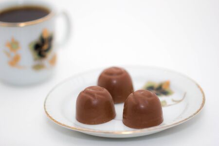 Chocolate candies and cup of coffee on a white backgroundの写真素材