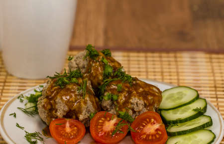 Meatballs with sauce on tha plate with cherry tomatoes and cucumberの写真素材