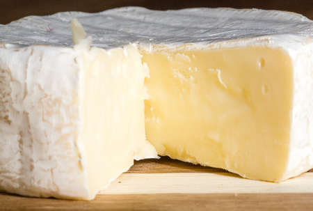 A head of brie cheese with one section cutの写真素材