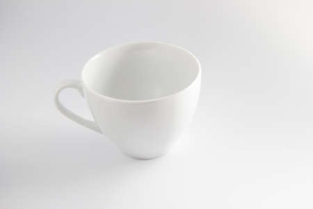 White coffee cup standing on a white surface
