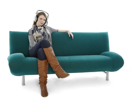 Woman sitting on sofa and listening to musicの写真素材