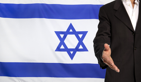 Businessman with an open hand waiting for a handshake concept for business with the Israel flag in the backgroundの写真素材