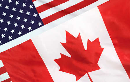 USA and Canada relations concept with diagonally merged real fabric flagsの写真素材