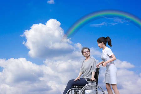 Under a blue sky with white clouds and rainbows, an elderly woman in a wheelchair and a Japanese woman in a white nursing uniform pushing the wheelchair are smiling and talking.3D illustrationの写真素材