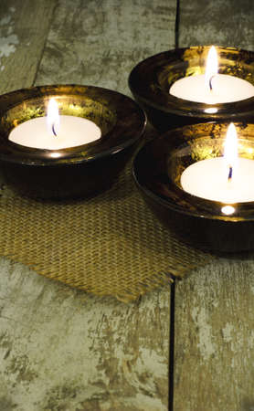 Three black and gold mottled tealight holder on a rustic tableの写真素材