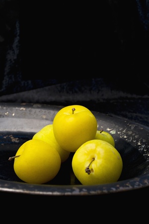 Fresh plums on an old serving dish, black velvet backgroundの写真素材