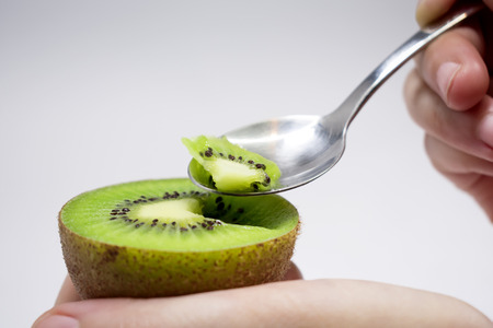 Spooning A Freshly Sliced Kiwi for Dessertの写真素材