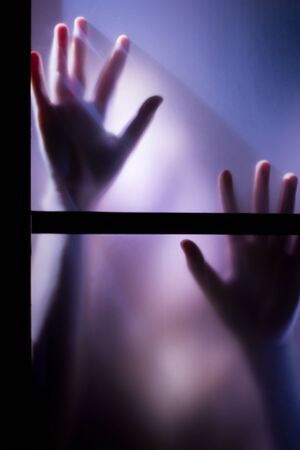 A Pair of a Woman's Hand Seen through a Frosted Glass Windowの写真素材