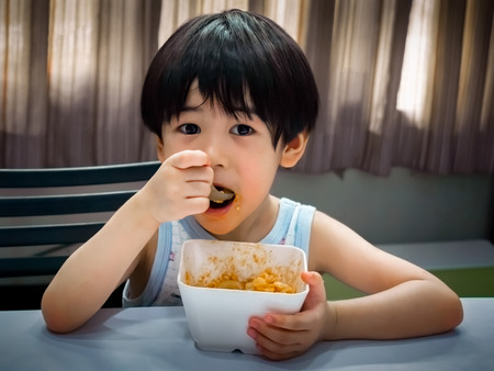 Independent Child Leaning to Eat on his Ownの写真素材