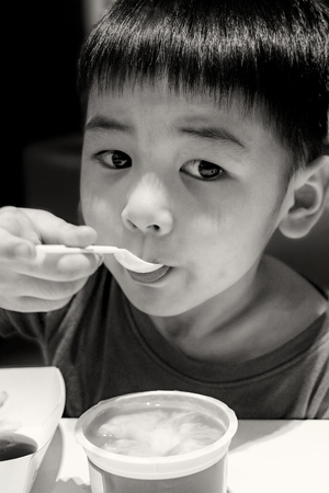Young Boy Eats Mashed Potato with a Plastic Spoonの写真素材