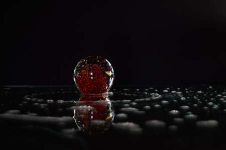 Glass ball on a surface with foam and black backgroundの写真素材