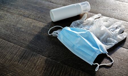 Coronavirus prevention travel. Protective mask, gloves and hand sanitizer on wooden background.