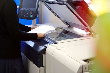Young woman making photocopies on a copy machine in office.