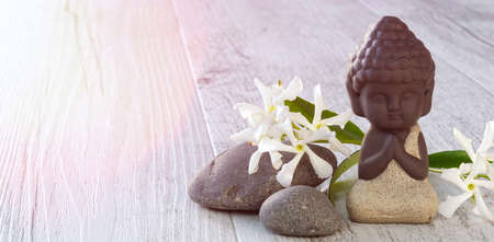 Little Buddha meditating with stones on wooden backgroundの写真素材