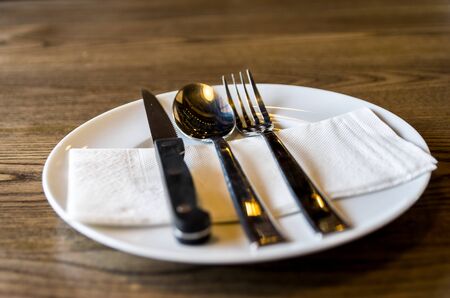 A set of knife, fork and spoon on wooden table