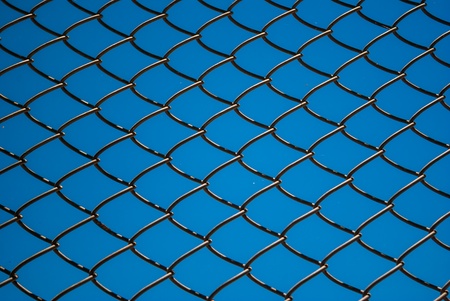 Metal mesh wire fence with blue sky backgroundの写真素材