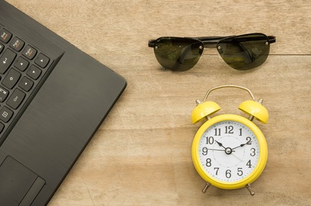 Black notebook  and yellow clock with eye glass on woodenbackground.の写真素材