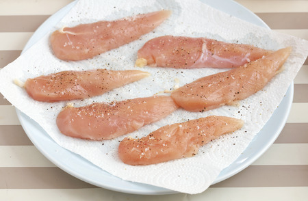 close up raw chicken with salt and pepper on dishの写真素材