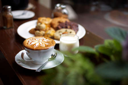 close up hot latte in white cup and cookiesの写真素材