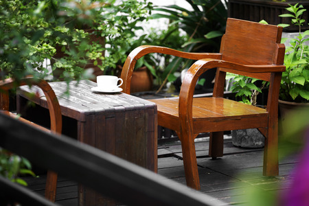 close up white cup and wooden chair in gardenの写真素材