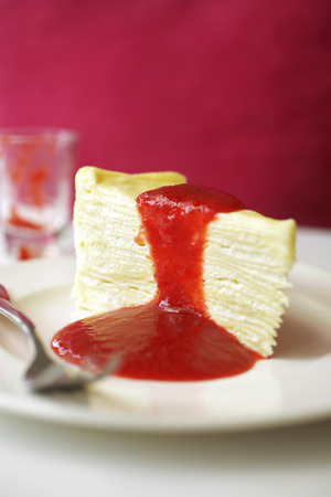 close up crepe cake and strawberry sauce in white dish