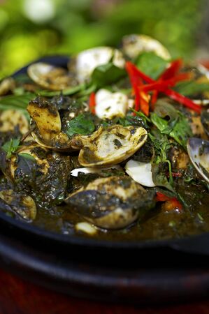 close up spicy shell and basil sauce fried in black dishの写真素材