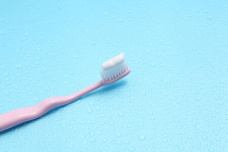pink toothbrush and water on blue background with a blank space for a text