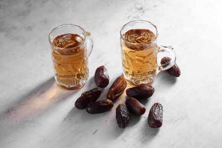 dates fruit juice in mini glass on a white concrete background with a blank space for a text, dates fruit juice on a white backgroundの写真素材