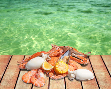 Seafood on wooden table with sea backgroundの写真素材