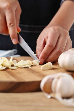 Chef chopped garlic on wooden cutting board in kitchen
