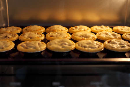 Mini pie from meat and mushrooms baking in industrial oven, Pie and pastry wholesale bakery factoryの写真素材