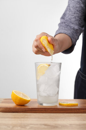 Woman make lemonade on wooden table in kitchenの写真素材