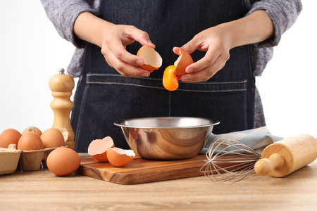 Woman hands to separate egg white and yolks with egg shells in kitchenの写真素材