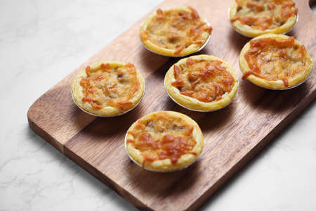 Mini pie from meat and mushrooms in wooden tray on marble background