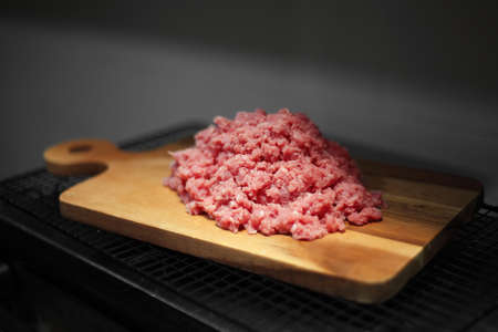 Minced meat on wooden cutting board in kitchenの写真素材