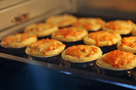 Mini pie from meat and mushrooms baking in industrial oven, Pie and pastry wholesale bakery factory