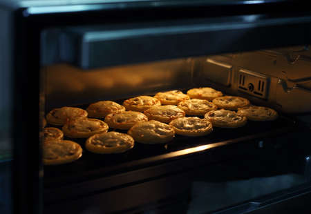 Mini pie from meat and mushrooms baking in industrial oven, Pie and pastry wholesale bakery factoryの写真素材