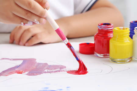 Asian boy use paintbrush and watercolor painting in white paper