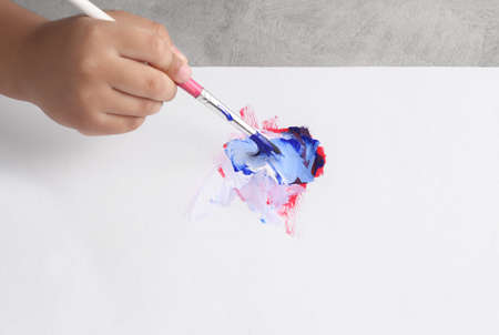 Asian boy use paintbrush and watercolor painting in white paperの写真素材