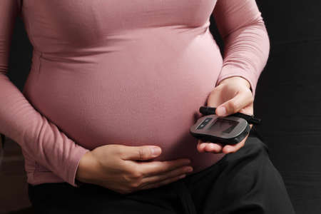 Pregnant woman holding blood sugar level meter, Pregnancy healthcareの写真素材