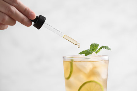Food stylist use dropper decorating iced tea with lemon in glass