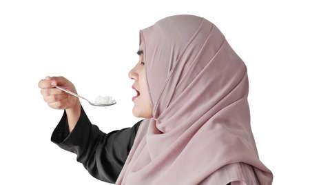 Muslim woman eating rice with spoon isolated on white background. Healthy eating concept.の写真素材