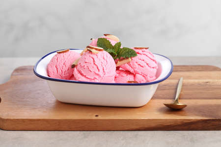 strawberry ice cream in white bowl on wooden cutting board