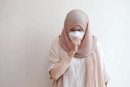 Muslim woman wearing a surgical mask feeling sick on pastel background. Covid-19 coronavirus concept. Copy space for text.の写真素材