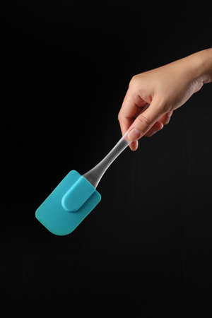 Hand holding cake spatula isolated on black backgroundの写真素材