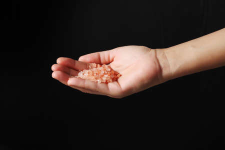 Hand holding pink salt isolated on black backgroundの写真素材